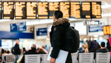 Man standing inside airport looking at flight schedule.